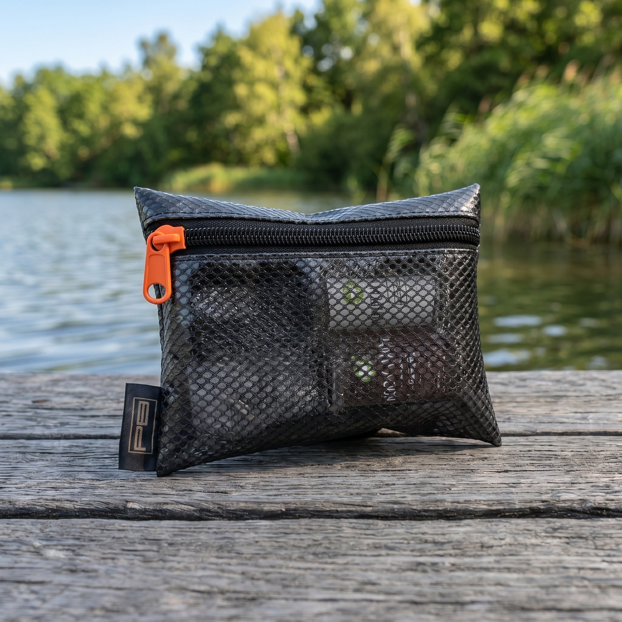 PB Products Carp Care mesh zip storage pouch holding the fish care sprays beside the water